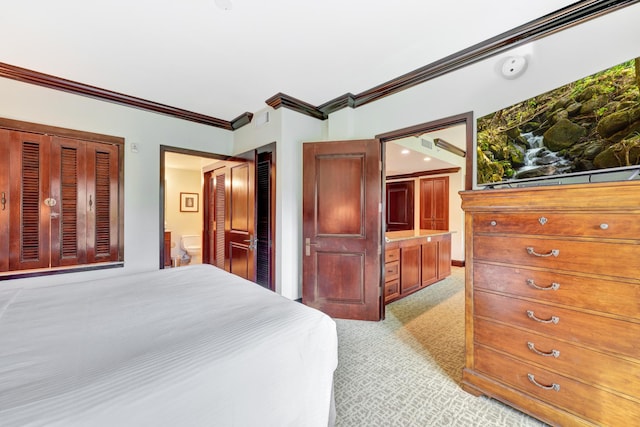 carpeted bedroom with ornamental molding and connected bathroom