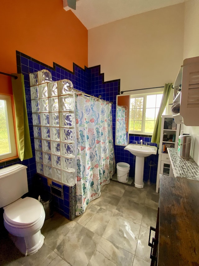 bathroom featuring sink, curtained shower, toilet, and tile walls