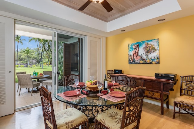 dining space featuring ceiling fan, ornamental molding, a raised ceiling, and light hardwood / wood-style flooring