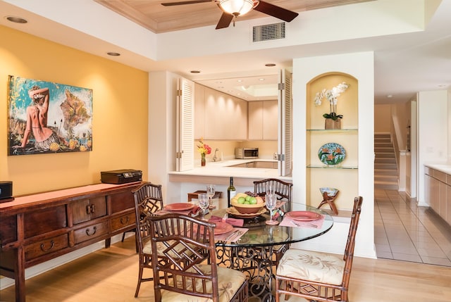 dining area featuring ceiling fan, a tray ceiling, and light hardwood / wood-style floors