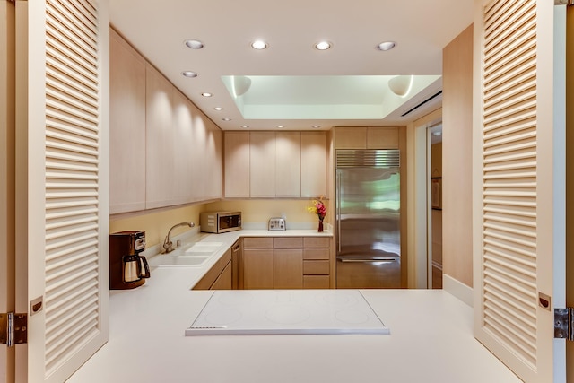 kitchen featuring built in refrigerator, kitchen peninsula, stovetop, and a raised ceiling