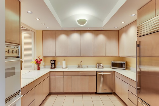 kitchen with stainless steel appliances, light brown cabinets, and sink