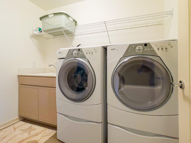 washroom with cabinets, sink, and washing machine and dryer