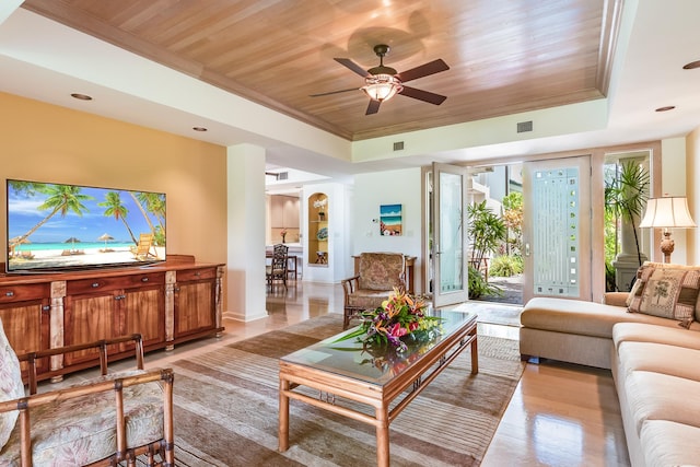 living room featuring ceiling fan, wooden ceiling, a raised ceiling, and a healthy amount of sunlight