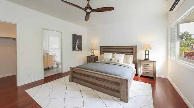 bedroom with a wall unit AC, ceiling fan, hardwood / wood-style floors, a walk in closet, and a closet