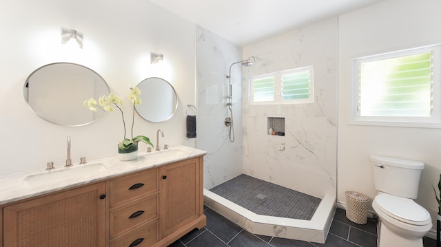 bathroom with a tile shower, toilet, tile patterned floors, and vanity