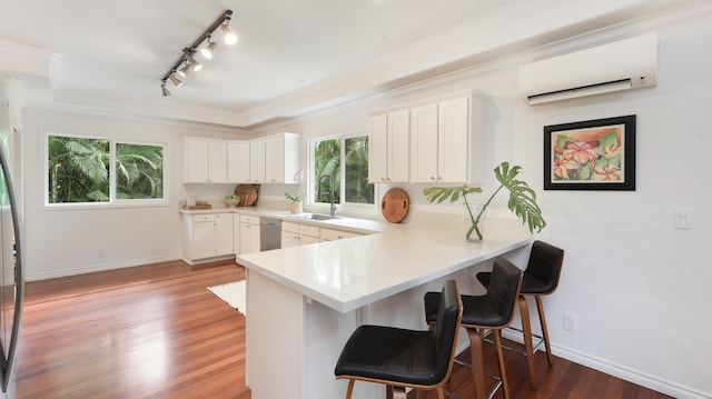 kitchen featuring white cabinets, a wall mounted air conditioner, kitchen peninsula, and sink