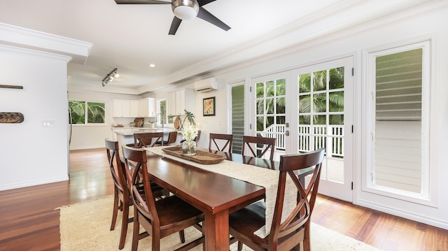 dining room with an AC wall unit, sink, french doors, light hardwood / wood-style flooring, and ceiling fan