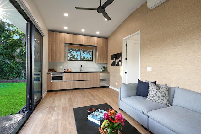 living room with light wood-type flooring, vaulted ceiling, ceiling fan, and sink