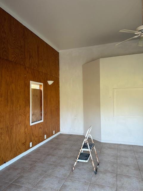 spare room with ceiling fan and wooden walls