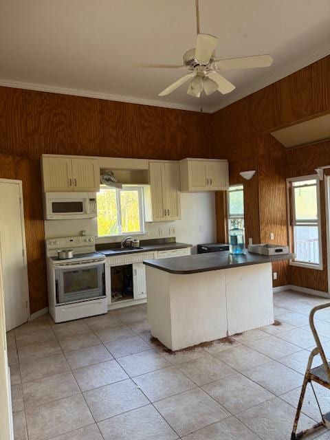 kitchen featuring ceiling fan, a center island, wood walls, white appliances, and ornamental molding