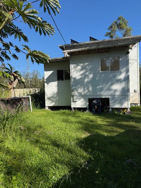 rear view of house featuring a lawn and a storage unit