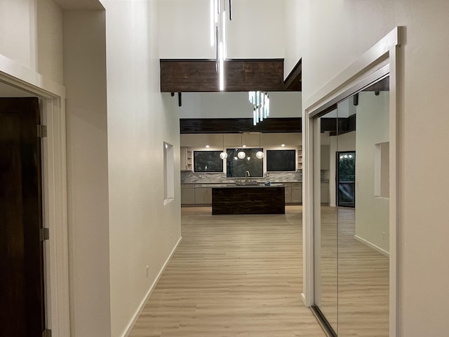 hallway with a towering ceiling and light hardwood / wood-style floors