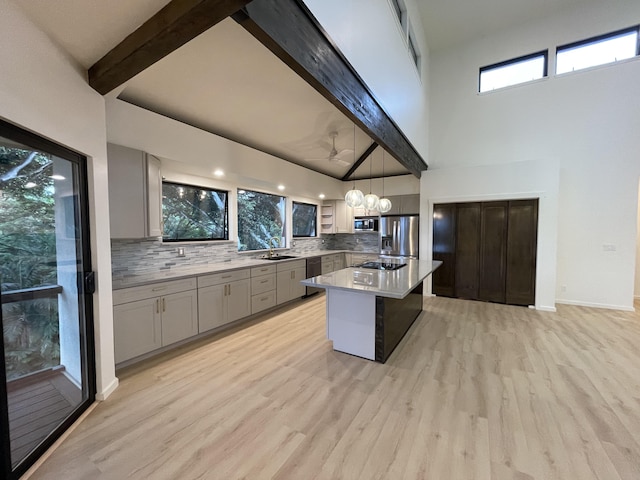 kitchen with tasteful backsplash, stainless steel appliances, beam ceiling, decorative light fixtures, and a kitchen island