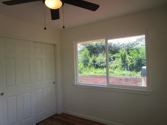 unfurnished bedroom with dark hardwood / wood-style flooring, ceiling fan, and a closet