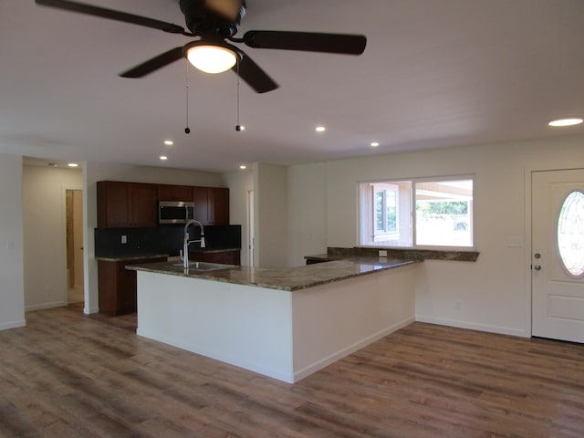 kitchen with hardwood / wood-style flooring, ceiling fan, dark stone countertops, and sink