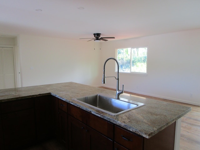 kitchen featuring light stone countertops, ceiling fan, sink, light hardwood / wood-style floors, and dark brown cabinets