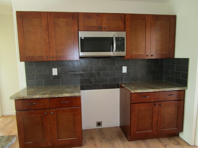 kitchen with tasteful backsplash, light hardwood / wood-style flooring, and light stone counters