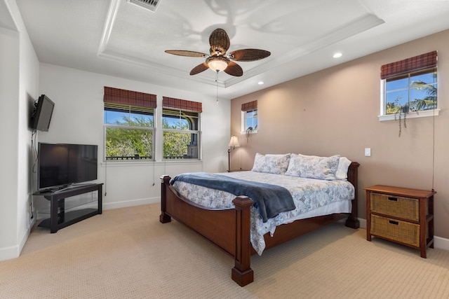 carpeted bedroom with a raised ceiling, multiple windows, and ceiling fan