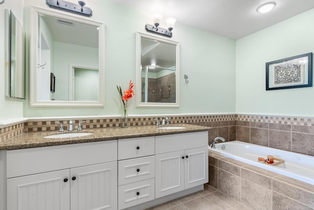 bathroom featuring tile patterned floors, vanity, and tiled tub