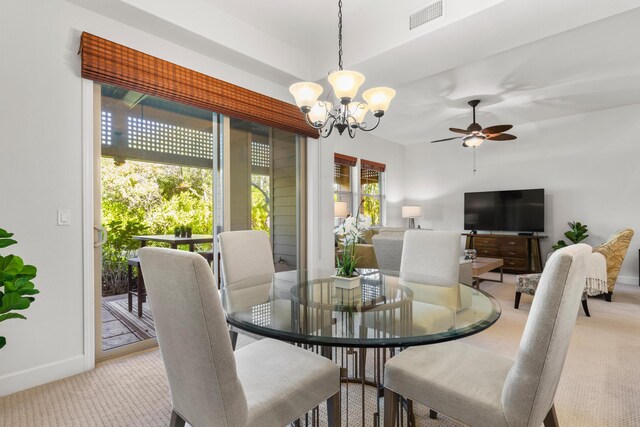 dining space with ceiling fan with notable chandelier and light colored carpet