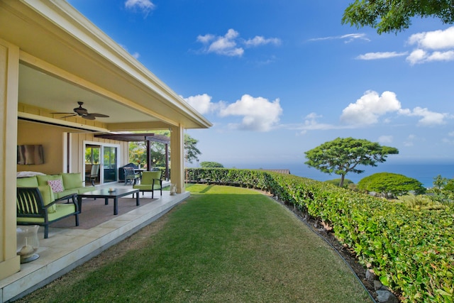 view of yard with outdoor lounge area, ceiling fan, a water view, and a patio