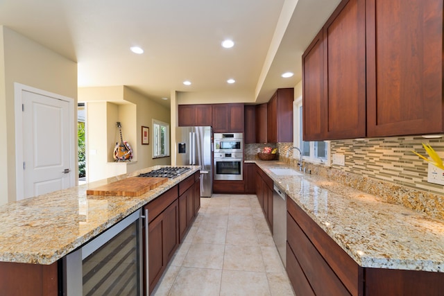 kitchen with light stone countertops, backsplash, stainless steel appliances, sink, and wine cooler