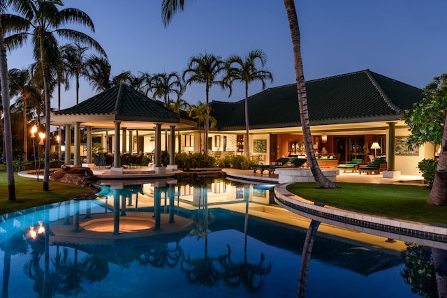 pool at dusk featuring a gazebo, a patio area, and a lawn