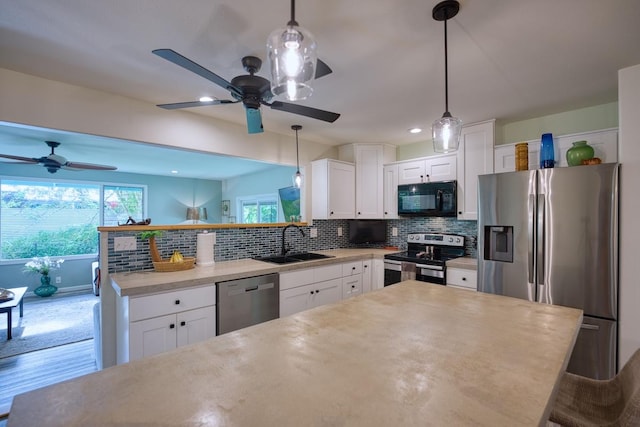 kitchen with stainless steel appliances, white cabinetry, tasteful backsplash, and sink