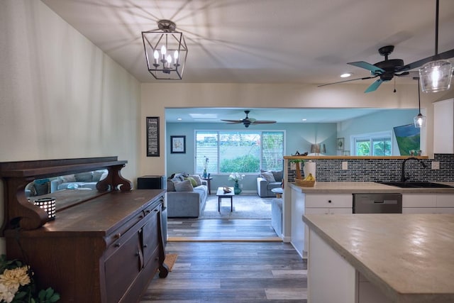 kitchen with white cabinetry, sink, hanging light fixtures, and stainless steel dishwasher