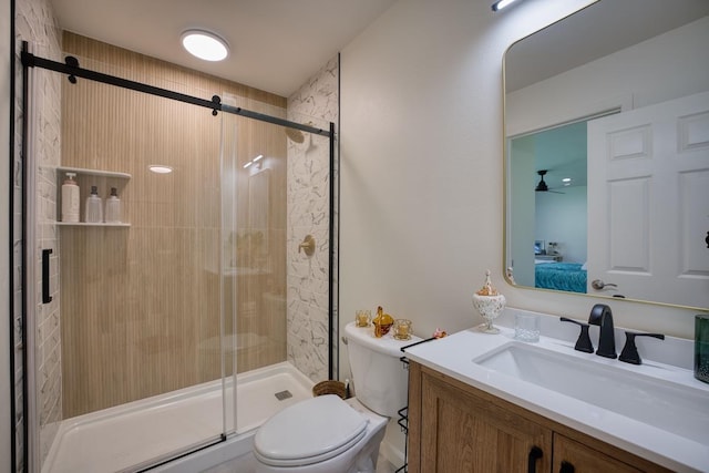 bathroom featuring vanity, toilet, a shower with door, and ceiling fan