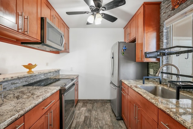 kitchen featuring dark wood-type flooring, sink, ceiling fan, light stone counters, and stainless steel appliances