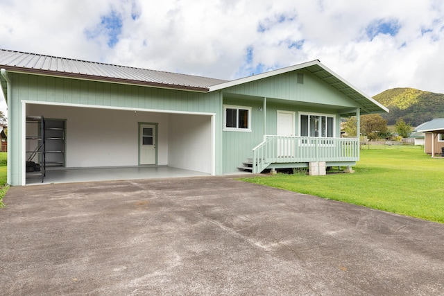 view of front facade with a mountain view, covered porch, a front yard, and a carport