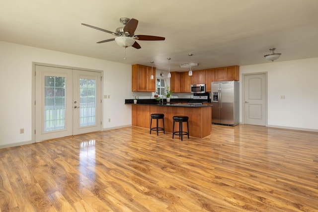 kitchen featuring ceiling fan, french doors, decorative light fixtures, a breakfast bar area, and appliances with stainless steel finishes