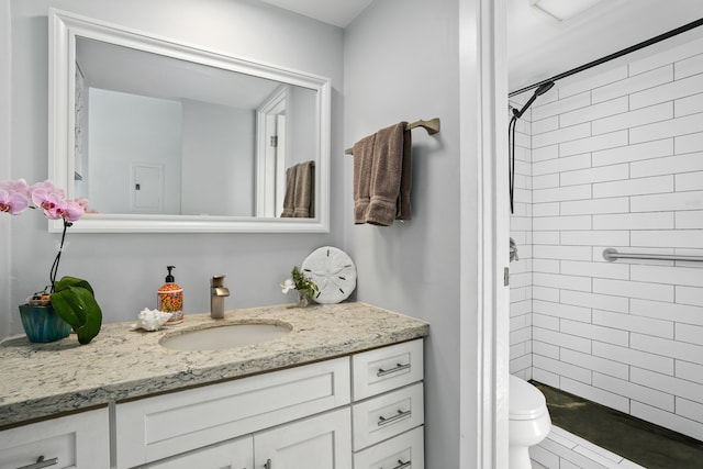 bathroom featuring toilet, vanity, and tiled shower