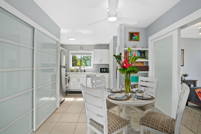 dining area featuring ceiling fan, sink, and light tile patterned flooring