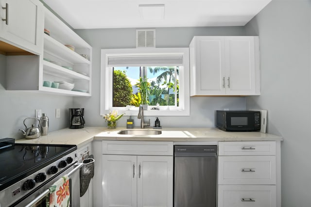 kitchen featuring white cabinets, appliances with stainless steel finishes, light stone counters, and sink