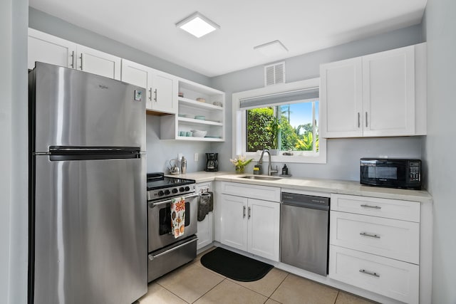 kitchen with light tile patterned flooring, stainless steel appliances, white cabinetry, and sink