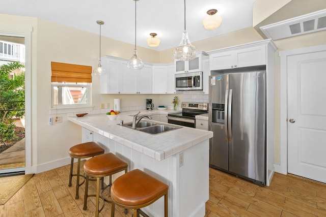 kitchen featuring a kitchen breakfast bar, white cabinetry, sink, and appliances with stainless steel finishes