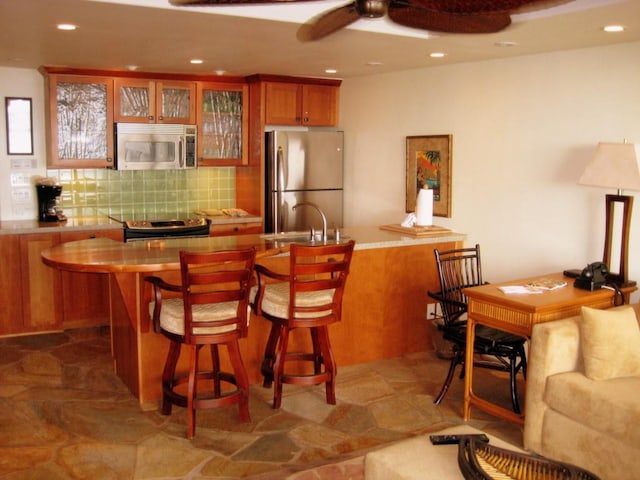 interior space with appliances with stainless steel finishes, sink, ceiling fan, and decorative backsplash