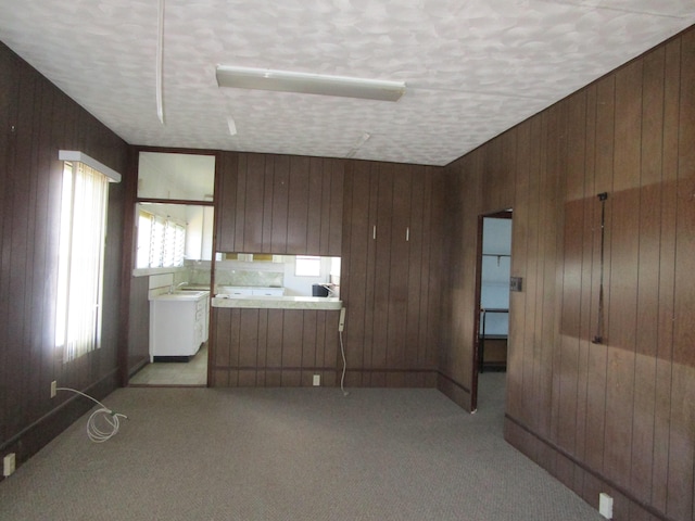 unfurnished room featuring a textured ceiling, light colored carpet, and wood walls