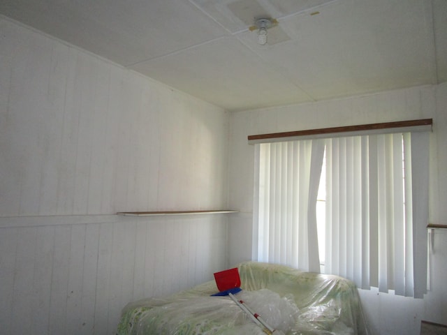 bedroom with ceiling fan and wood walls