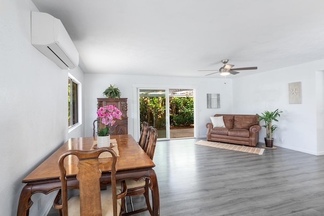 dining area with a wall unit AC, ceiling fan, a healthy amount of sunlight, and hardwood / wood-style floors