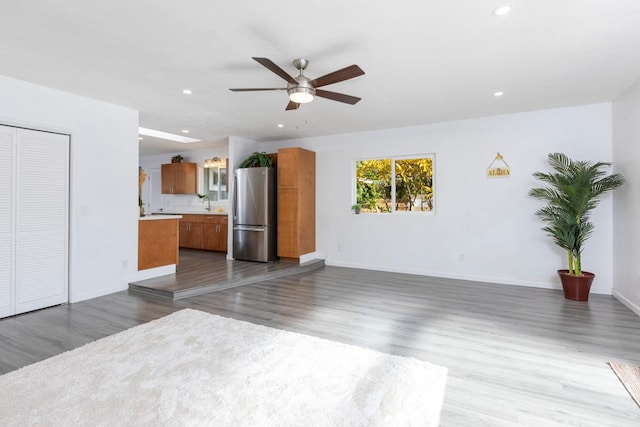 unfurnished living room with sink, wood-type flooring, and ceiling fan