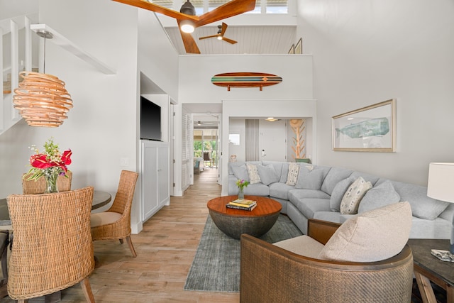 living room featuring light hardwood / wood-style flooring, high vaulted ceiling, and ceiling fan