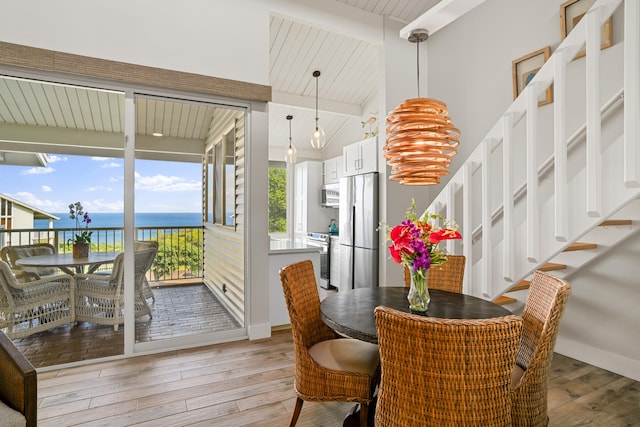 dining space with vaulted ceiling with beams, a water view, light hardwood / wood-style flooring, and wood ceiling