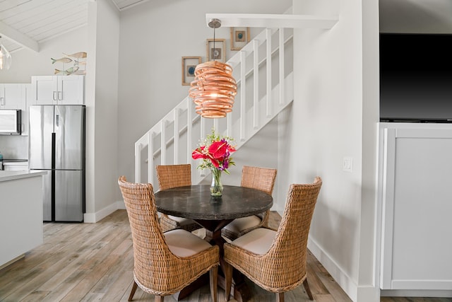 dining space with vaulted ceiling with beams, wooden ceiling, and light wood-type flooring