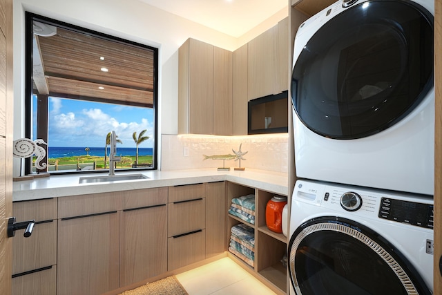 washroom featuring stacked washer / drying machine, light tile patterned flooring, cabinets, and sink