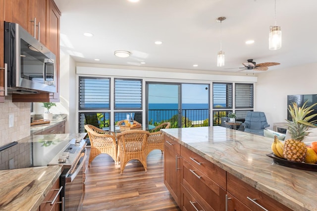 kitchen featuring light stone countertops, appliances with stainless steel finishes, dark wood-type flooring, tasteful backsplash, and ceiling fan