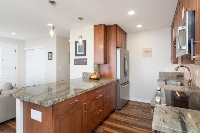 kitchen with stainless steel appliances, kitchen peninsula, hanging light fixtures, and light stone countertops